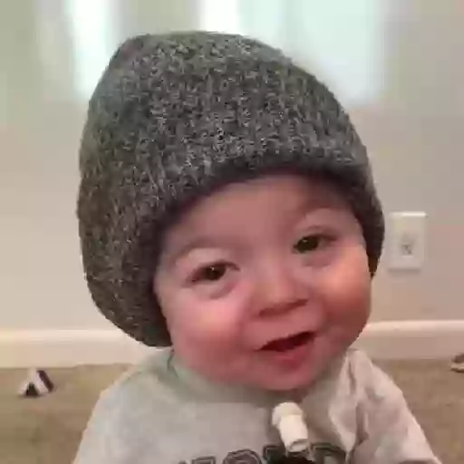 Figurinha: Bebê com touca brincando