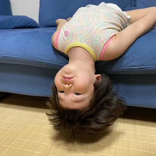 Figurinha: Criança de cabeça para baixo no sofá