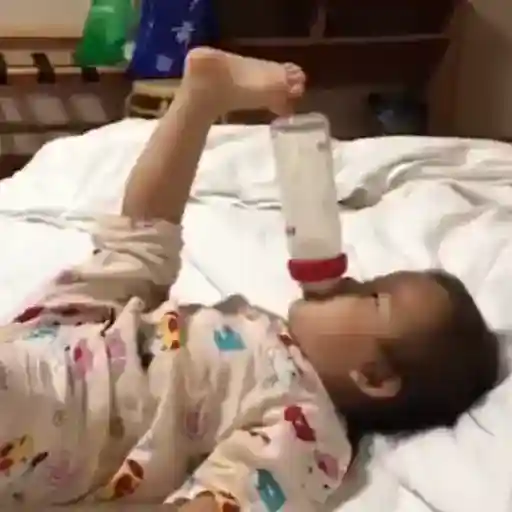 Figurinha: Bebê bebe leite com o pé