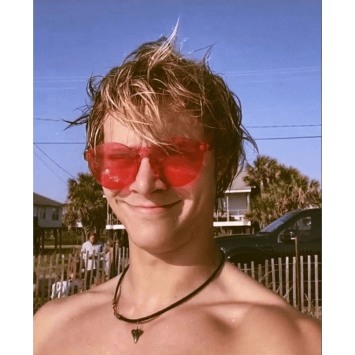 Figurinha: Jovem de óculos vermelhos em dia de sol